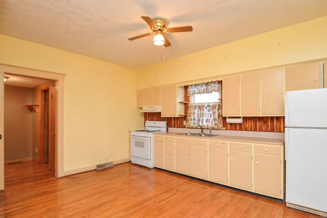 kitchen with white appliances, sink, and light hardwood / wood-style flooring