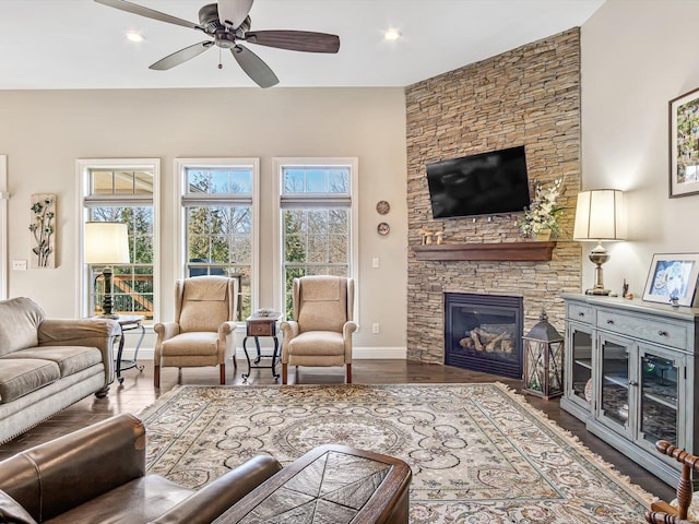 living room with hardwood / wood-style flooring, ceiling fan, and a stone fireplace