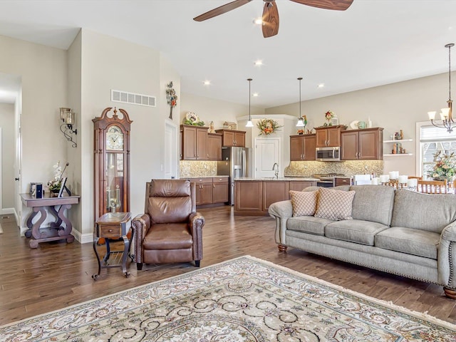 living room featuring dark wood-type flooring and ceiling fan with notable chandelier