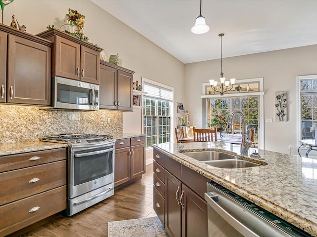 kitchen with stainless steel appliances, tasteful backsplash, sink, and light stone counters