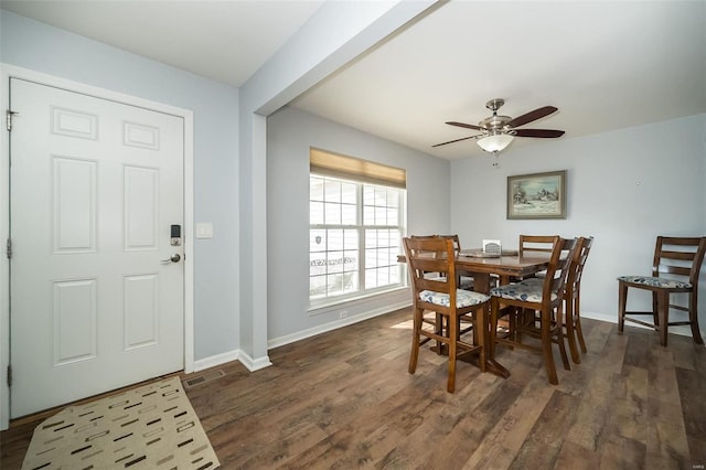 dining space featuring dark wood-style flooring, a ceiling fan, and baseboards