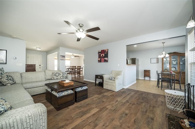 living area with baseboards, wood finished floors, and ceiling fan with notable chandelier