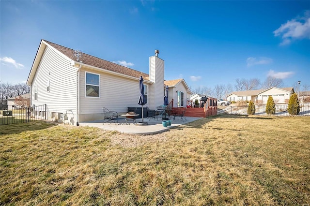 rear view of house featuring a chimney, a lawn, a patio area, and a fenced backyard