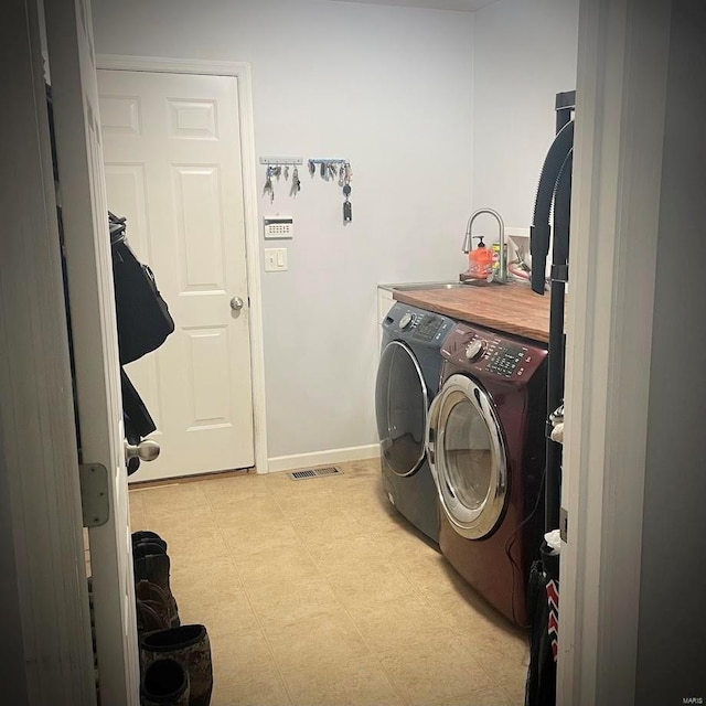 laundry area with light floors, washing machine and dryer, a sink, laundry area, and baseboards