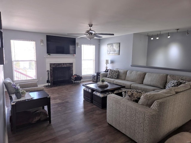 living area with a premium fireplace, a ceiling fan, dark wood-type flooring, and a wealth of natural light