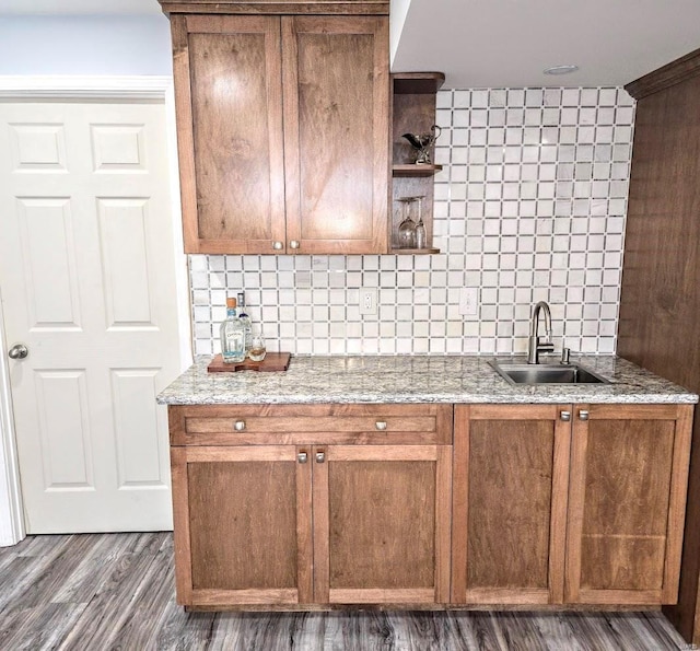 kitchen with decorative backsplash, light stone counters, open shelves, and a sink