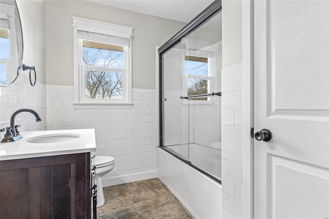 full bathroom featuring vanity, combined bath / shower with glass door, a healthy amount of sunlight, and toilet