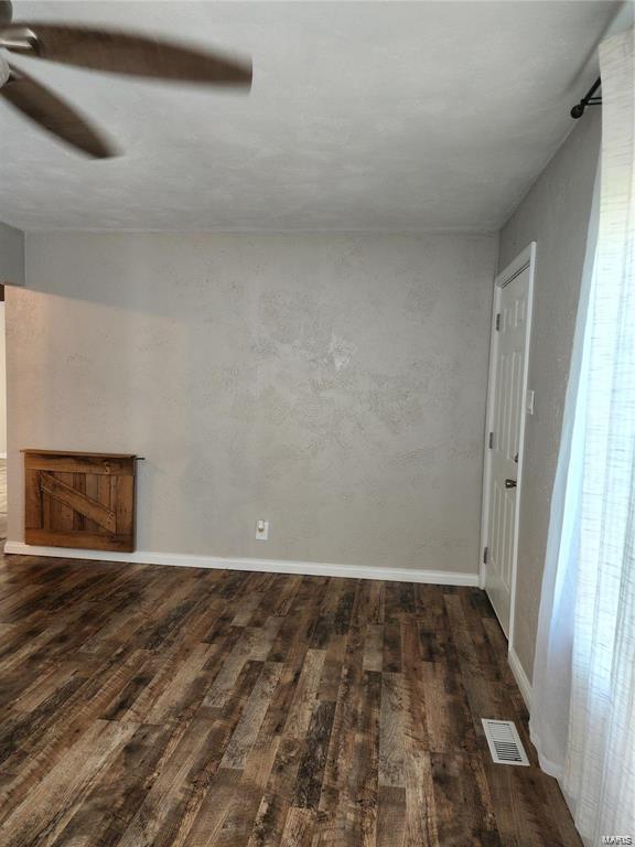 spare room featuring dark wood-type flooring and ceiling fan