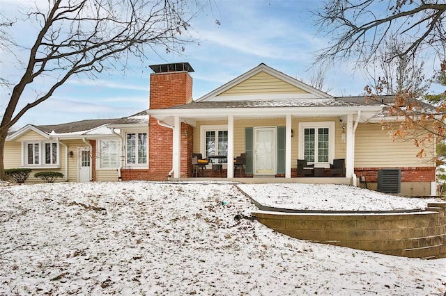 snow covered back of property featuring a porch