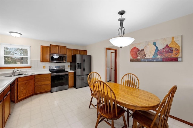 kitchen featuring hanging light fixtures, appliances with stainless steel finishes, sink, and decorative backsplash