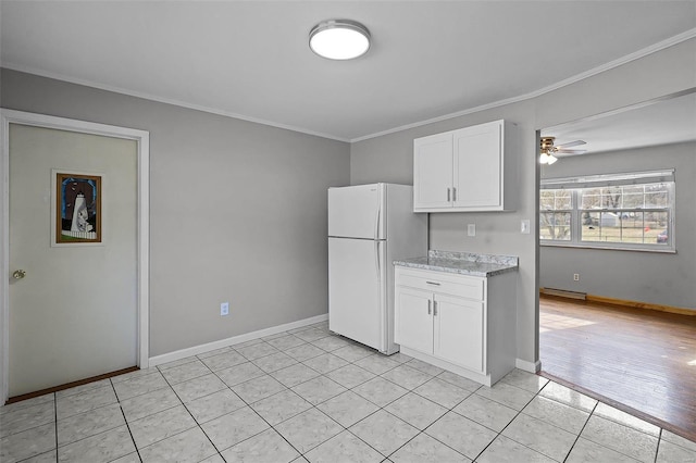 kitchen with light tile patterned floors, ornamental molding, white cabinets, and white refrigerator