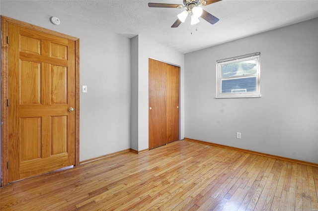 unfurnished bedroom featuring ceiling fan, a closet, a textured ceiling, and light wood-type flooring