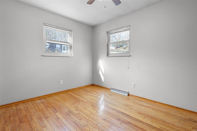 empty room featuring ceiling fan, a healthy amount of sunlight, and light hardwood / wood-style flooring