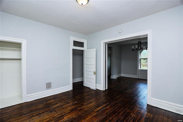 unfurnished bedroom featuring dark wood-type flooring and an inviting chandelier