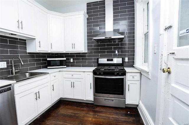 kitchen with wall chimney exhaust hood, sink, white cabinetry, tasteful backsplash, and appliances with stainless steel finishes