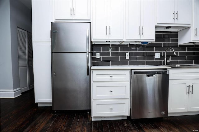 kitchen featuring appliances with stainless steel finishes, sink, white cabinets, backsplash, and dark wood-type flooring