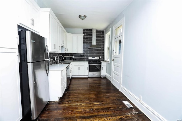 kitchen with appliances with stainless steel finishes, sink, white cabinets, dark wood-type flooring, and wall chimney exhaust hood