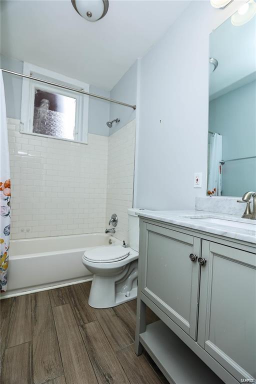 full bathroom featuring wood-type flooring, toilet, shower / tub combo, and vanity