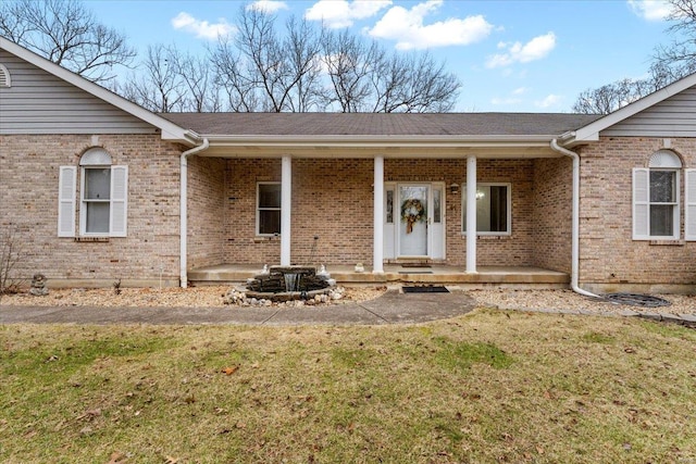 entrance to property featuring a porch and a lawn