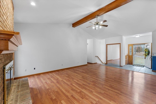 unfurnished living room with ceiling fan, a brick fireplace, vaulted ceiling with beams, and light wood-type flooring