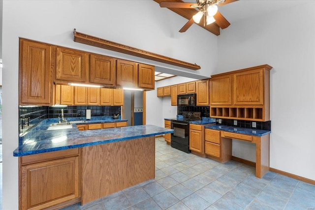 kitchen with a towering ceiling, black appliances, sink, backsplash, and kitchen peninsula