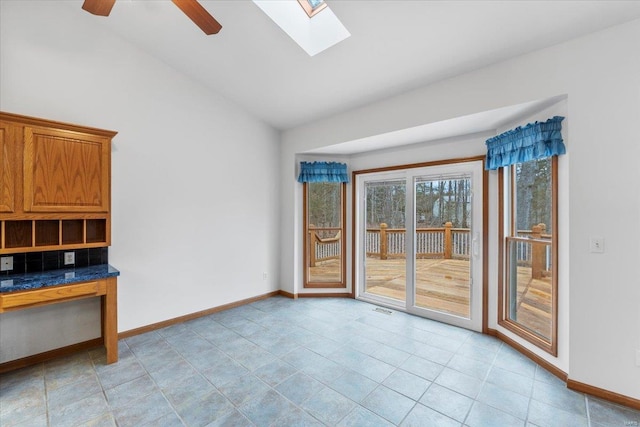 tiled spare room with ceiling fan and lofted ceiling with skylight