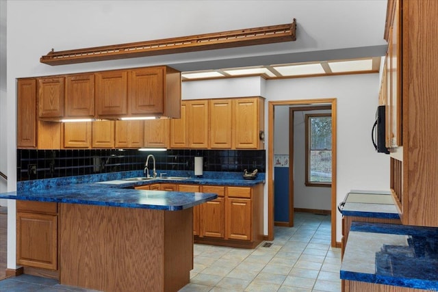 kitchen with sink, light tile patterned floors, decorative backsplash, and kitchen peninsula