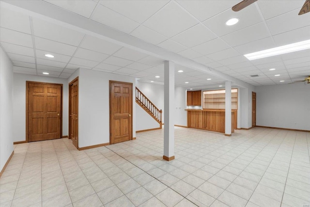 basement featuring ceiling fan and a drop ceiling