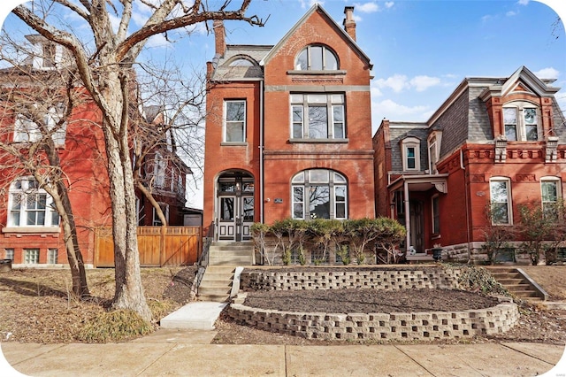 view of front facade with brick siding and fence