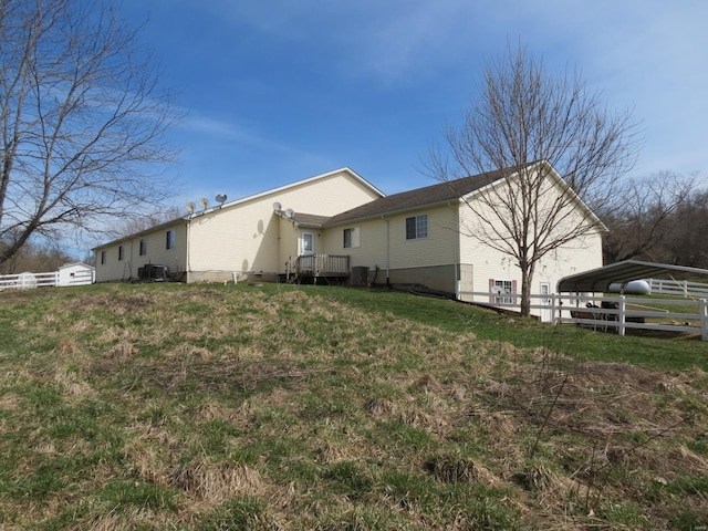 back of house with a carport, a lawn, and central air condition unit