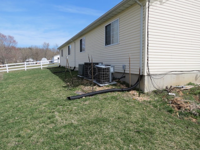 view of side of property featuring a yard and central AC