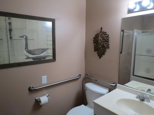 bathroom featuring vanity, toilet, and a shower with shower door