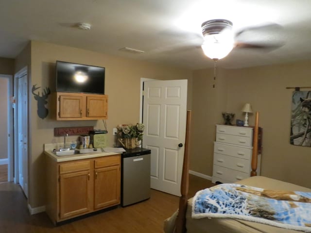 bedroom with stainless steel refrigerator, sink, and hardwood / wood-style floors