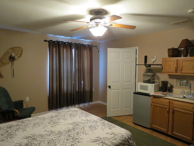 bedroom featuring ceiling fan, stainless steel fridge, and dark hardwood / wood-style flooring