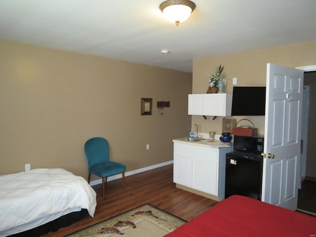 bedroom with dark hardwood / wood-style floors, refrigerator, and sink