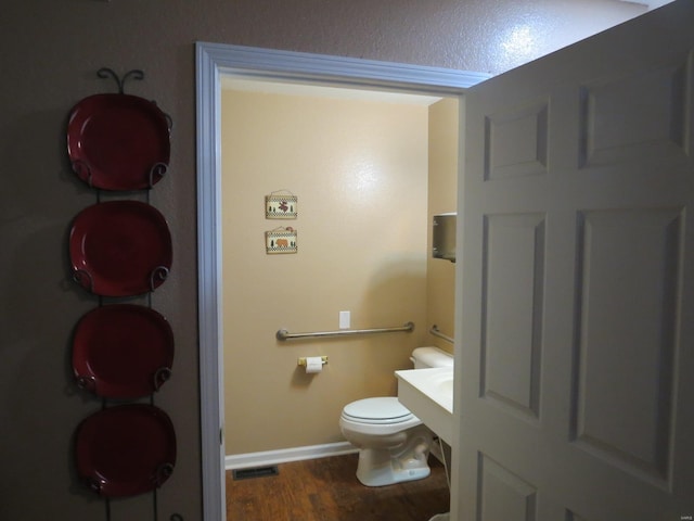 bathroom featuring hardwood / wood-style flooring and toilet