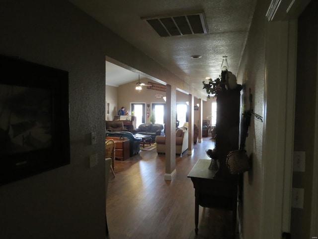 corridor with lofted ceiling, a notable chandelier, and wood-type flooring