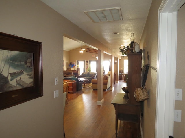 corridor with hardwood / wood-style flooring and lofted ceiling