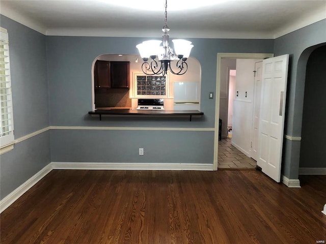 unfurnished dining area featuring dark wood-type flooring and an inviting chandelier