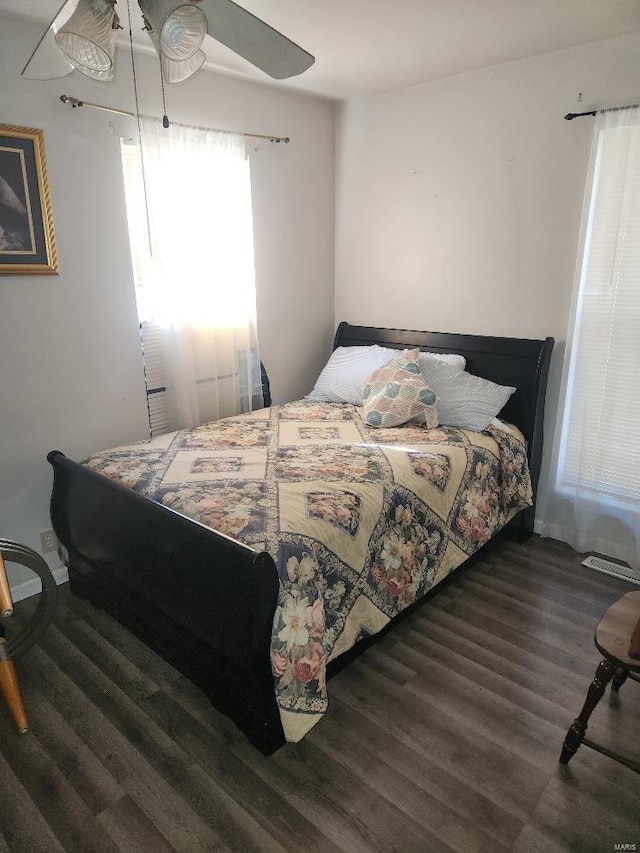 bedroom with ceiling fan, dark hardwood / wood-style flooring, and multiple windows