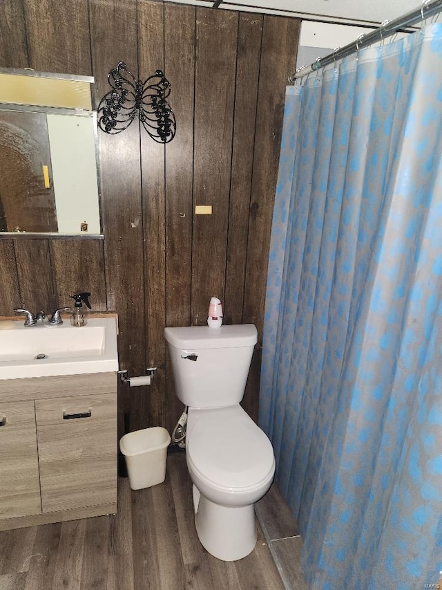 bathroom featuring wooden walls, vanity, toilet, and hardwood / wood-style floors