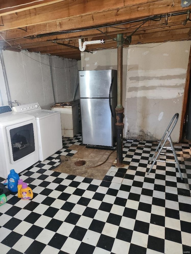 basement featuring washer and clothes dryer and stainless steel fridge