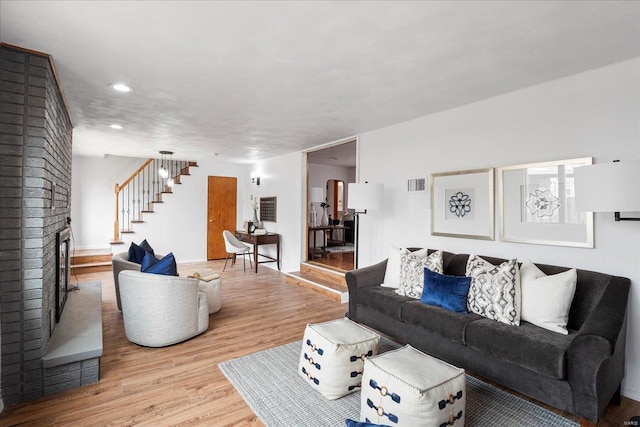 living room with a fireplace, recessed lighting, visible vents, wood finished floors, and stairs