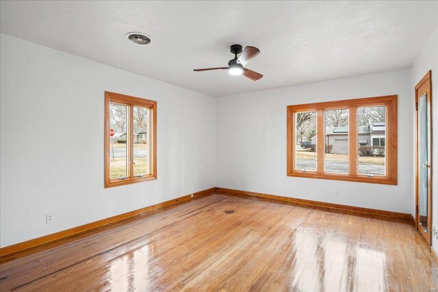 spare room featuring light wood finished floors, ceiling fan, and baseboards