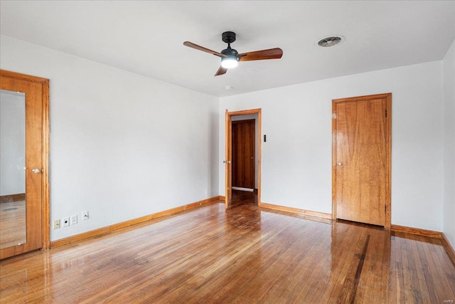 spare room with visible vents, ceiling fan, baseboards, and wood finished floors