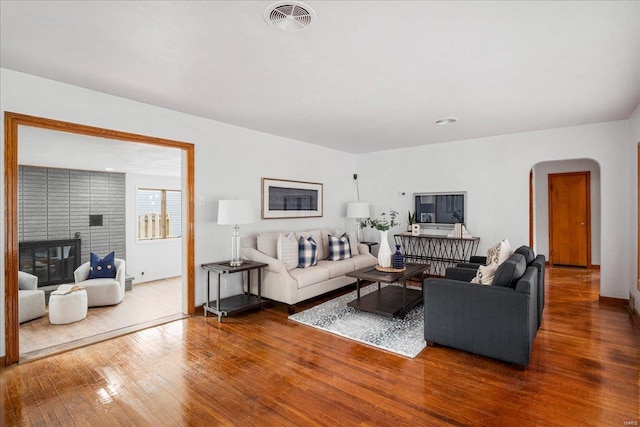 living room with arched walkways, hardwood / wood-style floors, and visible vents