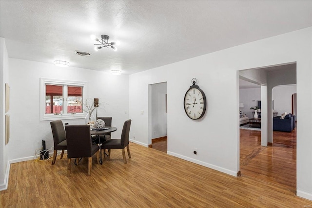 dining room with visible vents, light wood-style flooring, baseboards, and a textured ceiling