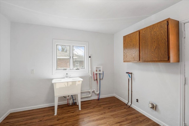 clothes washing area with hookup for a washing machine, cabinet space, baseboards, and wood finished floors