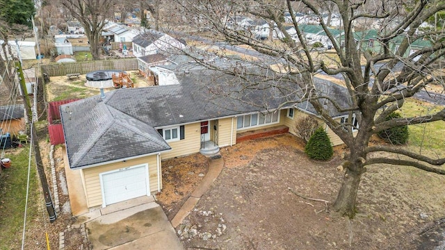 ranch-style home with a shingled roof, fence, and driveway