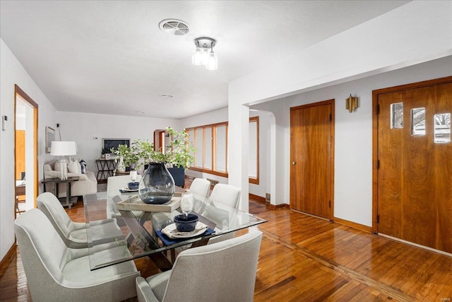 dining space with baseboards, visible vents, and hardwood / wood-style floors